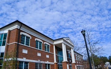 Coker University's red brick, two story library  on a beautiful, partly cloudy day.